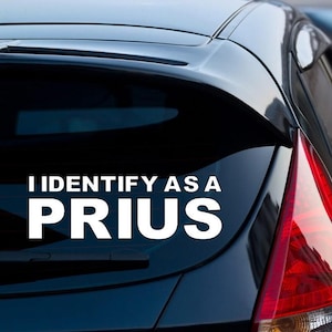 May include: A black car with a white vinyl sticker on the back window that says "I identify as a Prius".