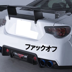 May include: White car rear with a black spoiler and exhaust pipes. The car has a black bumper and the Japanese characters "ファックオフ" are printed in black.