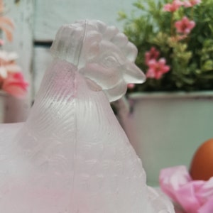 May include: A frosted glass chicken figurine with a detailed head and textured feathers. The figurine is a pale pink colour and has a delicate, vintage aesthetic.