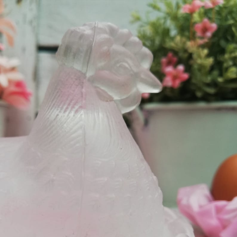 May include: A frosted glass chicken figurine with a detailed head and textured feathers. The figurine is a pale pink colour and has a delicate, vintage aesthetic.