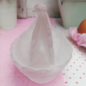 May include: A frosted glass dish shaped like a rooster with a detailed head and comb. The dish is white and has a scalloped edge.