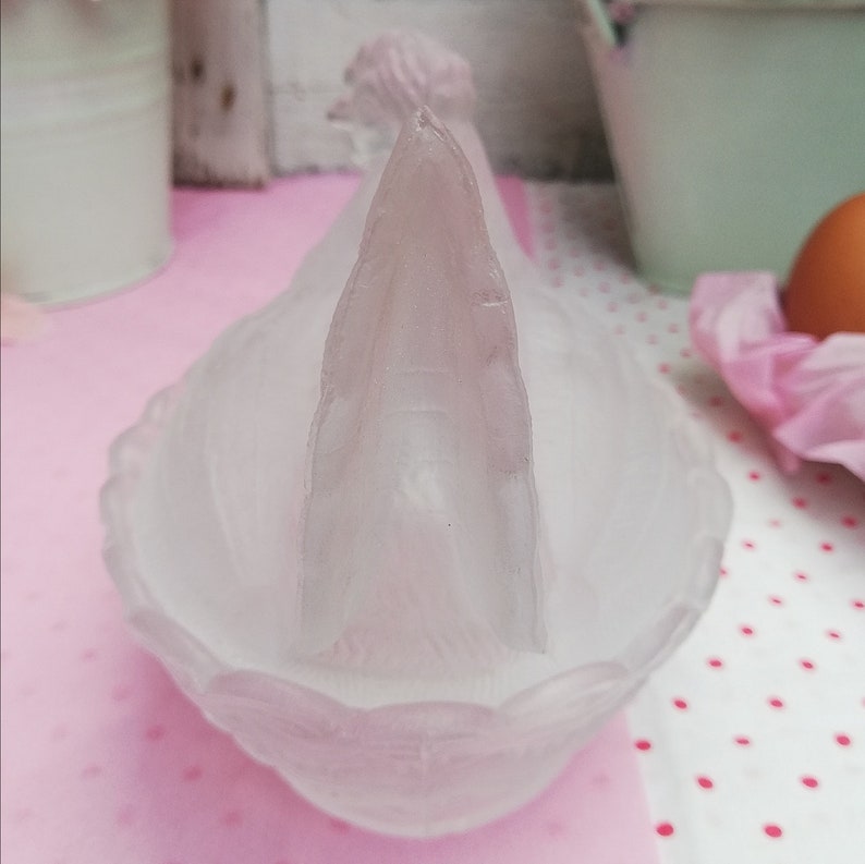 May include: A frosted glass dish shaped like a rooster with a detailed head and comb. The dish is white and has a scalloped edge.