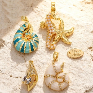 Può includere: Quattro ciondoli dorati a tema marino. Uno è un design a forma di cavalluccio marino e stella marina con perle finte. Un altro è una conchiglia di nautilus con smalto turchese. Il terzo è una conchiglia con smalto bianco e cristalli. Il quarto è un ciondolo di cristallo. Una piccola etichetta recita "Hand Made."