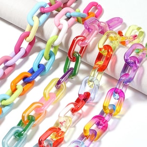 Puede incluir: Surtido de cadenas de plástico de colores. Las cadenas están hechas de plástico opaco y tienen un efecto de degradado de color. Las cadenas están dispuestas en una fila sobre una superficie blanca.