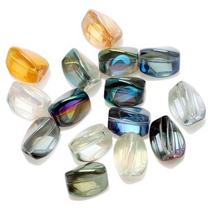Pode incluir: Uma variedade de contas de vidro iridescentes em v&aacute;rias cores, incluindo &acirc;mbar, verde-azulado e transparente. As contas t&ecirc;m uma forma retangular arredondada com um acabamento polido, que reflete a luz. Ideal para a cria&ccedil;&atilde;o de joias.