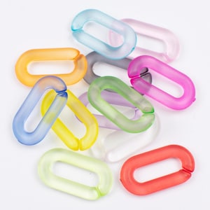 Puede incluir: Una colección de coloridos eslabones de cadena de plástico translúcido en varios tonos, incluyendo azul, naranja, amarillo, verde, rosa y rojo. Los eslabones ovalados tienen una abertura dividida, sobre un fondo blanco.
