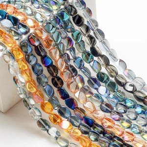 Pode incluir: Fios de contas ovais em v&aacute;rias cores, incluindo azul, laranja e transparente. As contas t&ecirc;m uma superf&iacute;cie facetada, criando um efeito brilhante. Ideais para a cria&ccedil;&atilde;o de joias, estas contas oferecem uma gama de tons para designs criativos.