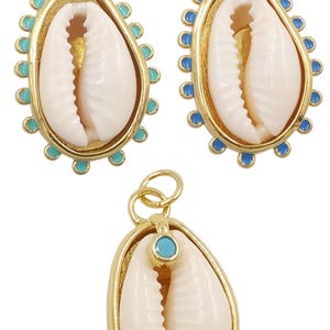 Op de afbeelding: Drie goudkleurige schelpenhangers. Elke hanger heeft een witte schelp, omlijst door een gouden frame met turquoise of blauwe accenten. De hangers zijn ontworpen met een lus aan de bovenkant om op te hangen.