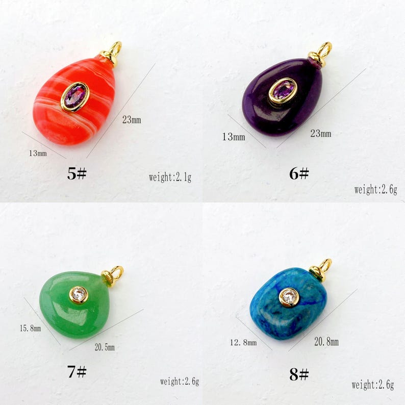 Puede incluir: Cuatro colgantes de piedras preciosas en rojo, morado, verde y azul, cada uno con una fianza dorada. Los colgantes rojos y morados tienen una piedra de forma ovalada en el centro. Los colgantes verdes y azules tienen una piedra redonda en el centro. Medidas en mil&iacute;metros.