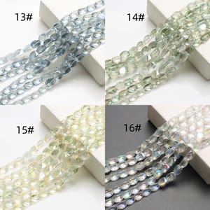 Pode incluir: Quatro conjuntos de contas ovais em v&aacute;rias cores: azul claro, verde, amarelo e branco iridescente. Cada conjunto &eacute; rotulado com um n&uacute;mero. As contas s&atilde;o enfiadas, prontas para fazer joias ou outros projetos de artesanato.