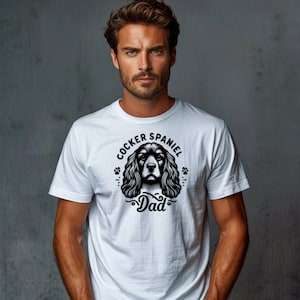 May include: White t-shirt with a black and white illustration of a Cocker Spaniel dog with the text "Cocker Spaniel Dad" above the dog.