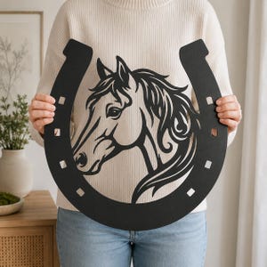 May include: A matte black metal wall art piece shaped like a horseshoe with a cutout design of a horse head in the center. The horseshoe features six square nail holes along its curved frame, showcasing a clean, flat, and solid silhouette.