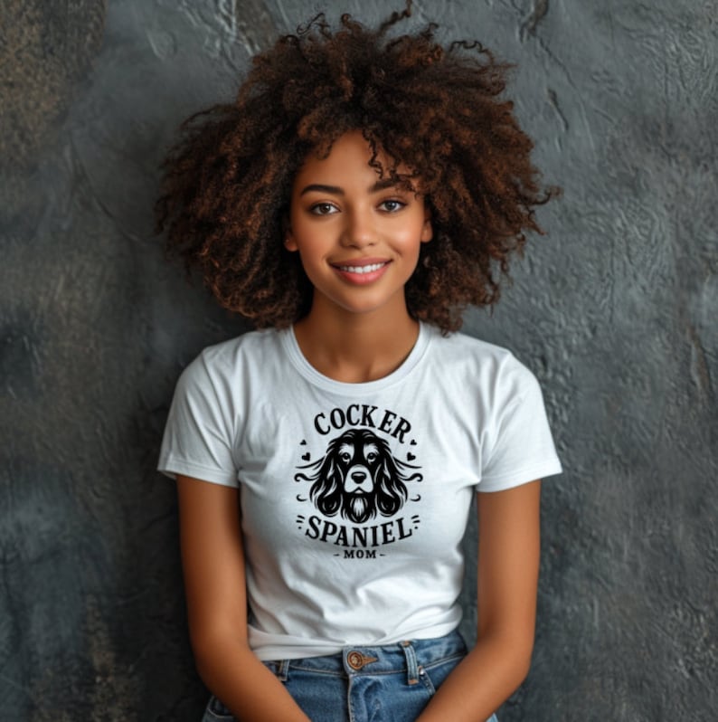 May include: A white t-shirt with a black graphic of a cocker spaniel dog head with the text "Cocker Spaniel Mom".