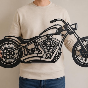 Könnte beinhalten: Ein Wandkunstobjekt aus schwarzem Metall in Form eines Motorrads. Das Design zeigt die detaillierte Silhouette eines Cruiser-Motorrads mit sichtbaren Motorkomponenten, Speichenrädern, Lenker und Scheinwerfer in flacher Scherenschnittoptik.