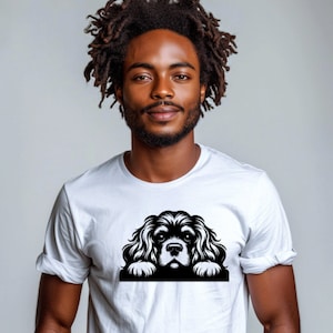 May include: A white t-shirt with a black and white illustration of a Cavalier King Charles Spaniel dog peeking over the top.