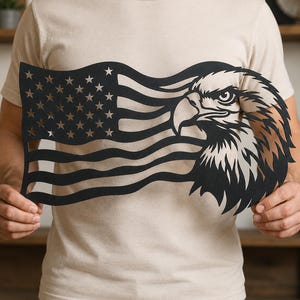 May include: Black metal wall art depicting an American flag with an eagle's head. The flag design features stars and stripes, with the eagle's head in profile. The eagle has detailed feathers and a sharp beak. The art is held by a person.