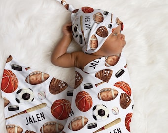 May include: A white swaddle blanket with a sports theme. The blanket features a variety of sports equipment, including basketballs, footballs, baseballs, and hockey pucks. The blanket is personalized with the name "Jalen".