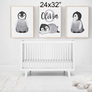 May include: Three framed prints featuring watercolor illustrations of penguins. The middle print has the name "Olivia" written in a decorative font.
