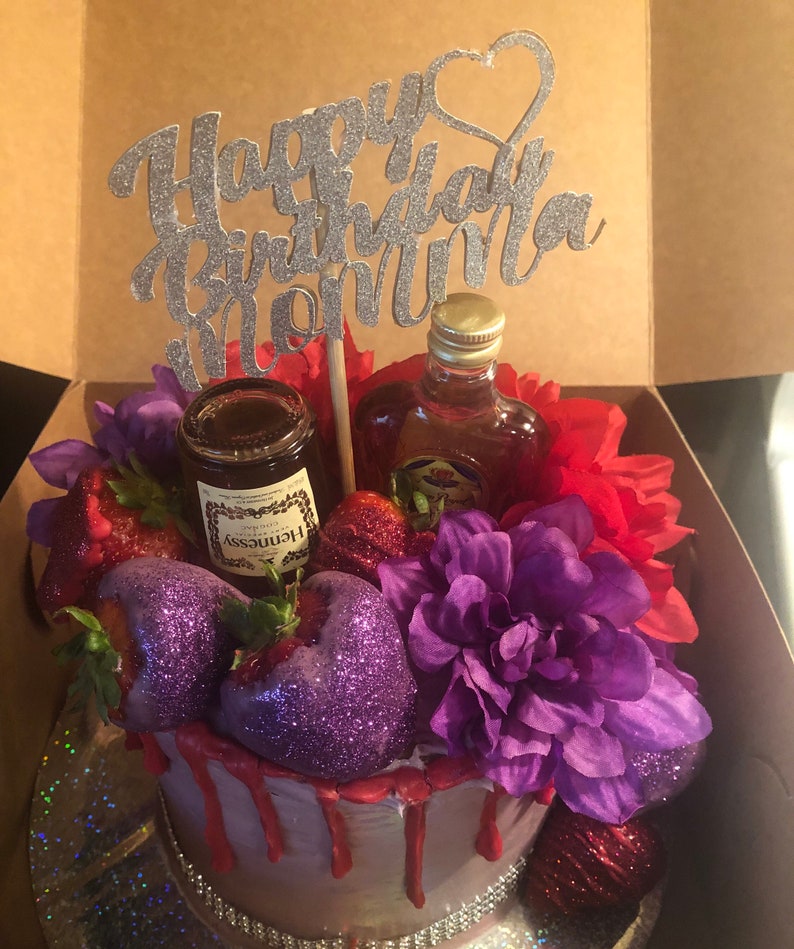 K&ouml;nnte beinhalten: Ein lila-roter Geburtstagskuchen mit einer Flasche Hennessy und einer Flasche Lik&ouml;r. Der Kuchen ist mit Erdbeeren, Blumen und einem "Happy Birthday Mom"-Topper verziert.