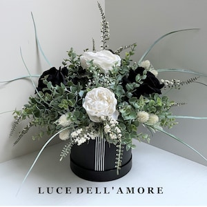 Composition florale dans une boîte à chapeaux noire : fausses pivoines et roses en velours
