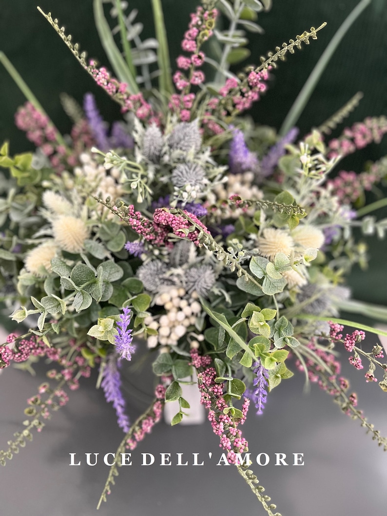 May include: A bouquet of purple and pink flowers with white accents. The flowers are arranged in a vase and the text "LUCE DELL'AMORE" is visible at the bottom of the image.