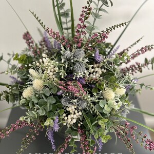 May include: A bouquet of artificial flowers in shades of purple, white, and green. The bouquet includes sprigs of lavender, eucalyptus, and thistle. The text "LUCE DELL'AMORE" is visible at the bottom of the image.