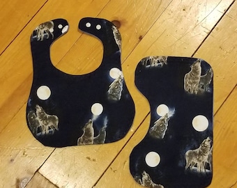 May include: Two blue fabric baby bibs with a wolf howling at the moon pattern. The bibs are made of a soft, absorbent material and are perfect for keeping baby's clothes clean.