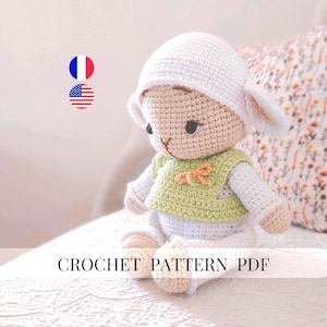 May include: A crocheted lamb doll wearing a white hat with floppy ears, a light green vest, and white pants. The doll has black eyes and a small orange bow. The text "CROCHET PATTERN PDF" is displayed below the doll.