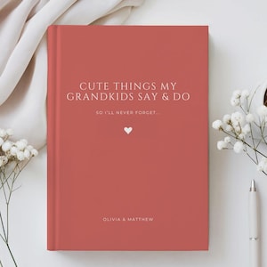 May include: A terracotta-colored hardcover journal with white text that reads: CUTE THINGS MY GRANDKIDS SAY & DO, SO I'LL NEVER FORGET..., and the names OLIVIA & MATTHEW. A small white heart icon is centered between the text on the front cover.