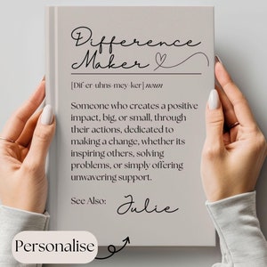 Peut inclure: Un journal beige avec le texte "Difference Maker" en écriture cursive noire. Le journal contient une définition du terme "Difference Maker" et le nom "Julie" écrit en cursive. Le texte "Personnaliser" est écrit dans un cercle avec une flèche pointant vers le journal.