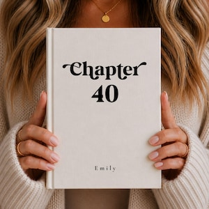 May include: A cream-coloured book with the text "Chapter 40" in black script. The name "Emily" is printed below. The book is held by a person wearing a beige jumper.