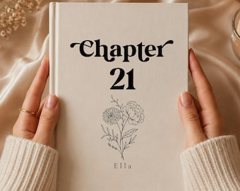 May include: A cream-colored hardcover book featuring the black text "Chapter 21" centered at the top, followed by a delicate black line-art illustration of a floral bouquet and the name "Ella" printed in a simple serif font at the bottom.