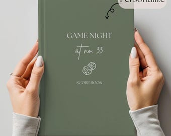 Könnte beinhalten: Ein grünes Buch mit dem Text "GAME NIGHT at no. 33" und "SCORE BOOK" in Weiß. Das Buch hat eine kleine Illustration von zwei Würfeln.
