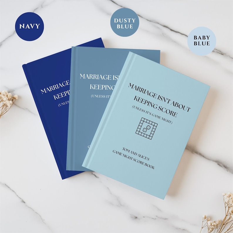 May include: Three hardcover score books in navy, dusty blue, and baby blue. Each cover features the text "MARRIAGE ISN'T ABOUT KEEPING SCORE (UNLESS IT'S GAME NIGHT)", a board game icon with dice, and "TOM AND ALICES GAME NIGHT SCORE BOOK" printed in black.