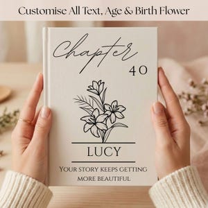 Peut inclure: Un livre à couverture rigide de couleur crème avec du texte noir et un dessin au trait floral. La couverture affiche les mots Chapter 40, le nom LUCY et la phrase YOUR STORY KEEPS GETTING MORE BEAUTIFUL, centrés autour d'un lys.