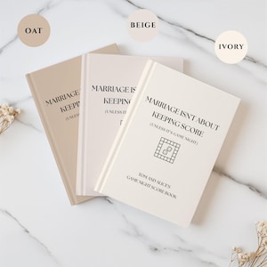 May include: Three score books in oat, beige, and ivory colors. Each book features the black text: MARRIAGE ISN'T ABOUT KEEPING SCORE (UNLESS IT'S GAME NIGHT), a board game icon with dice, and the text TOM AND ALICE'S GAME NIGHT SCORE BOOK.