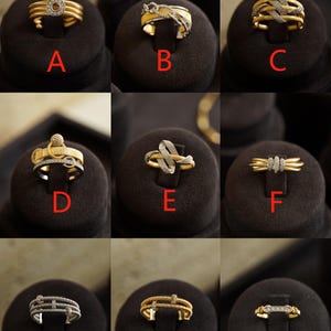 Pu&ograve; includere: Nove anelli in oro e argento con dettagli in diamanti, esposti su supporti in velluto nero. Gli anelli presentano diversi design, tra cui una fascia semplice con un solo diamante, una fascia intrecciata con diamanti e una fascia con pi&ugrave; file di diamanti.