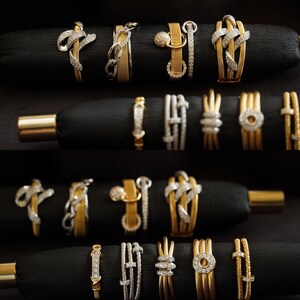 Pu&ograve; includere: Una collezione di anelli in oro e argento con dettagli in diamanti, esposti su velluto nero. Gli anelli presentano diversi design, tra cui un anello a catena, un nodo e un cerchio.