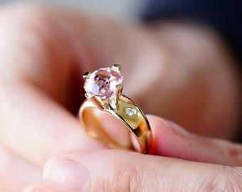 Può includere: Un anello d'oro con una grande pietra preziosa rosa e un piccolo accento di diamante.