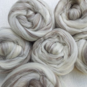 Può includere: Sei palle di rovaglio di lana bianca e marrone. Il rovaglio è disposto in un motivo circolare.