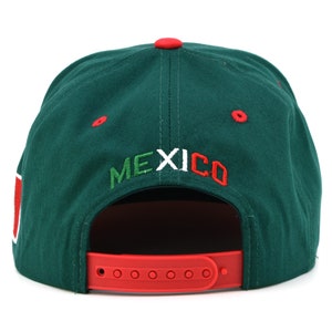 Puede incluir: Una gorra de b&eacute;isbol verde con visera roja y correa blanca. La gorra tiene la palabra "MEXICO" bordada en la parte posterior en verde, blanco y rojo.