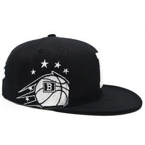 May include: Black baseball cap with a white basketball and stars embroidered on the front. The basketball has a white "B" inside.