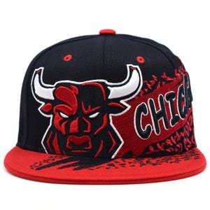 Könnte beinhalten: Eine schwarz-rote Chicago Bulls Baseballkappe. Die Kappe zeigt ein rotes Bullenlogo mit weißen Akzenten und das Wort "CHICAGO" in weißen Buchstaben. Der Schirm ist rot und die Kappe hat einen flachen Schirm.