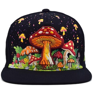 Puede incluir: Una gorra de béisbol negra con un hongo central bordado de colores vivos, con sombrero rojo y blanco y tallo naranja. El estampado circundante muestra una escena forestal con varios hongos coloridos, follaje verde y pequeñas motas amarillas.