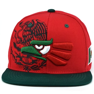Puede incluir: Una gorra de b&eacute;isbol roja y verde con un dise&ntilde;o de &aacute;guila mexicana bordado. La gorra tiene una visera verde y un &aacute;guila en blanco y negro en la parte delantera.