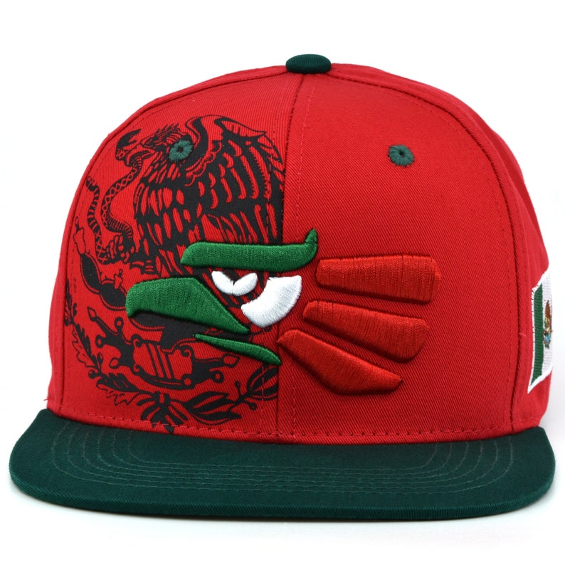 Puede incluir: Una gorra de b&eacute;isbol roja y verde con un dise&ntilde;o de &aacute;guila mexicana bordado. La gorra tiene una visera verde y un &aacute;guila en blanco y negro en la parte delantera.
