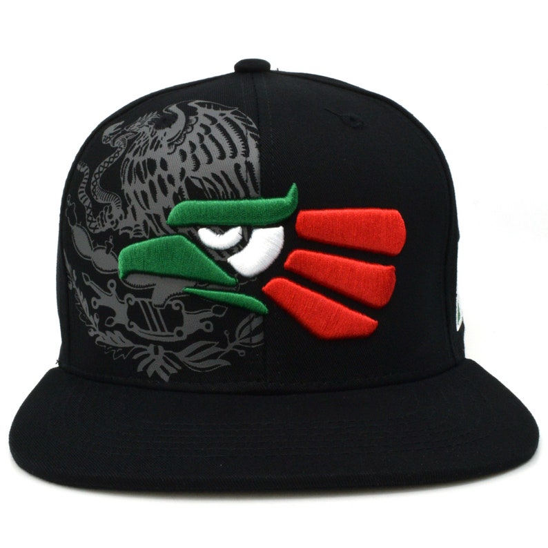 Puede incluir: Gorra de b&eacute;isbol negra ajustada con un dise&ntilde;o de &aacute;guila mexicana bordada. El &aacute;guila est&aacute; dividida en dos, con el lado izquierdo mostrando un &aacute;guila gris con cabeza verde y el lado derecho mostrando un &aacute;guila roja, blanca y verde.