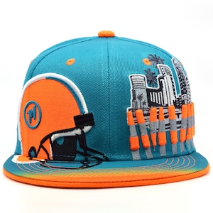Könnte beinhalten: Türkis-orangefarbene Baseballkappe mit flachem Schirm. Die Kappe hat ein orangefarbenes Footballhelm-Design an der Seite und eine Skyline mit Palmen. Der Schirm ist orange und der obere Knopf ist orange.