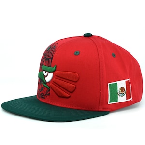 Puede incluir: Una gorra de b&eacute;isbol roja y verde con un &aacute;guila bordada y la bandera mexicana en el lateral.