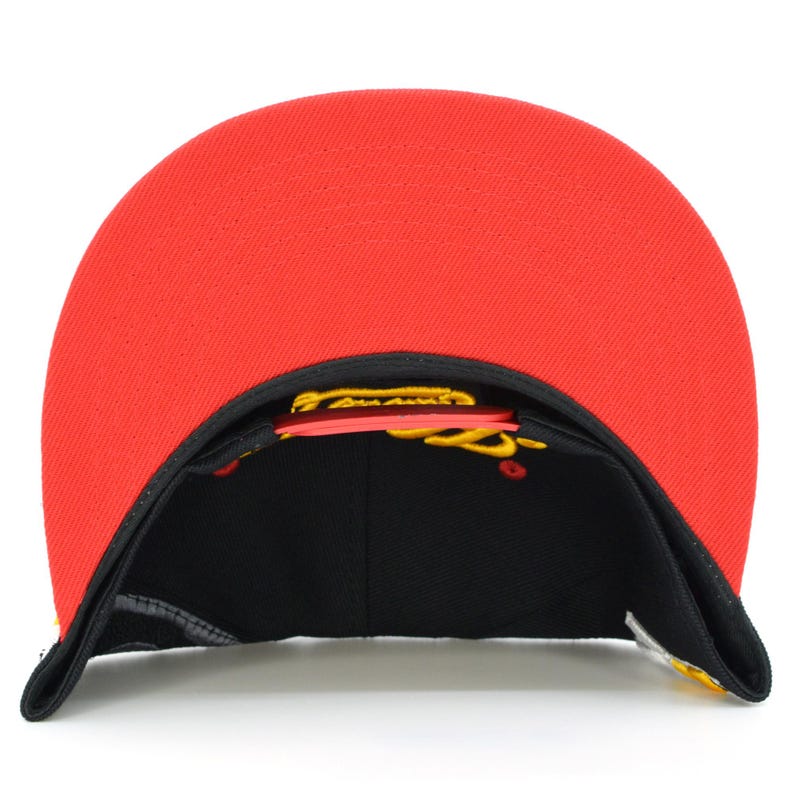 May include: A black and red baseball cap with a yellow embroidered logo. The cap has a flat brim and a structured crown.